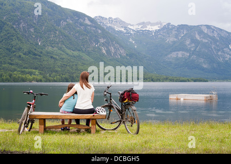 Madre e figlia insieme seduta su una panca in legno dal lago di Bohinj, Slovenia Gorenjska Alpi Giulie. Foto Stock