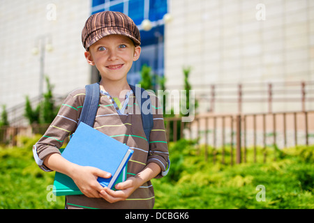 Giovani allegro scolaro con libri di fronte all edificio scolastico Foto Stock