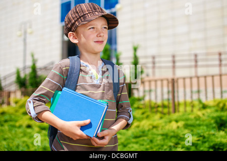 Giovani pensieroso kid di fronte all edificio scolastico Foto Stock