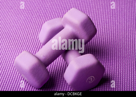 Viola pesi su un viola materassino yoga Foto Stock