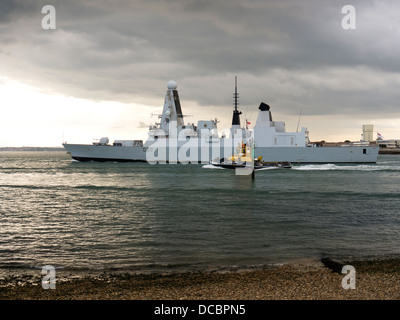 Il tipo di classe 45 cacciatorpediniere HMS audace, D32, lasciando il porto di Portsmouth accompagnata dal rimorchiatore indipendenti SD Foto Stock