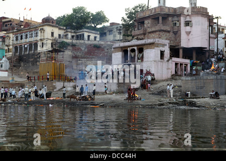 Persone in lutto si riuniranno presso la masterizzazione ghats sulle rive del fiume Gange, Varanasi. Foto Stock