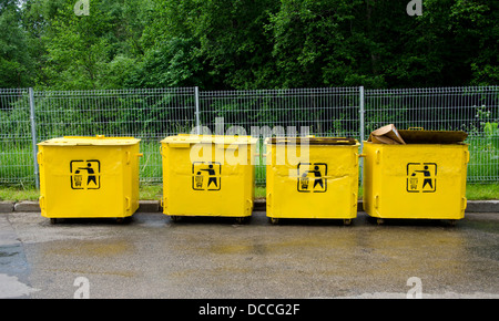 Quattro vecchie gialle trashcans nel posto di parcheggio Foto Stock