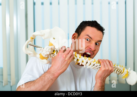 Ritratto di un pazzo terapista nella sua pratica, si morde in un backbone o spina dorsale Foto Stock