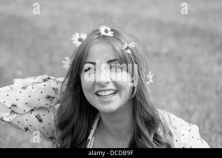 Orizzontale, immagine in bianco e nero di un felice, sorridente giovane donna con una catena a margherita nei suoi capelli Foto Stock