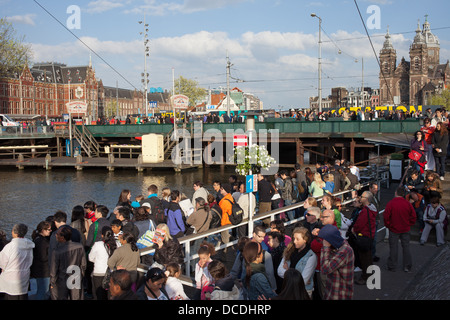 Gruppo di persone sul molo in attesa di canal bus vicino alla Stazione Ferroviaria Centrale di Amsterdam, Olanda, Paesi Bassi. Foto Stock
