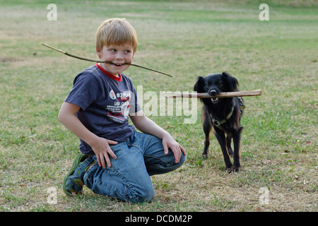 Ritratto di un giovane ragazzo e un cane con un bastone nella loro mouthes Foto Stock