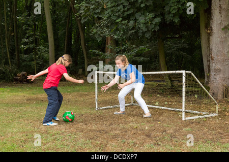 Due giovani ragazze che giocano a calcio nel cortile/giardino Foto Stock