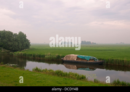 La mattina presto misty canal e barca Frisia Olanda Foto Stock