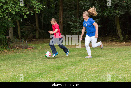 Due giovani ragazze che giocano a calcio nel cortile/giardino Foto Stock