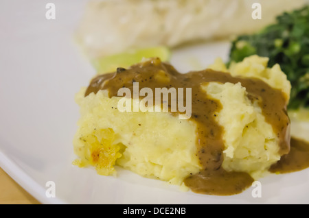 Close up di purè di patate con il sugo di carne sul piatto bianco Foto Stock