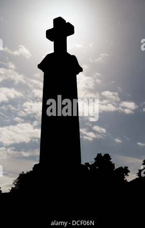 Oggetto contrassegnato per la rimozione definitiva croce in silhouette contro il cielo drammatico al cimitero Foto Stock