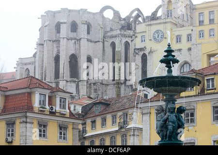 Fontana nella piazza del Rossio Lisbona, con le rovine del Carmo convento in background. Foto Stock