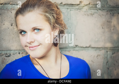 Giovane ragazza Blue-Eyed vicino a un muro di mattoni Foto Stock