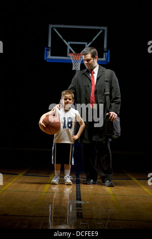 Giovane ragazzo in piedi sul campo da pallacanestro con suo padre Foto Stock