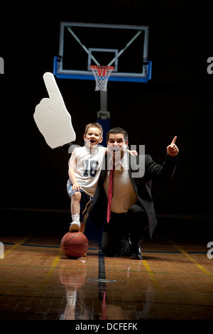 Giovane ragazzo in piedi sul campo da pallacanestro con suo padre cercando felice Foto Stock