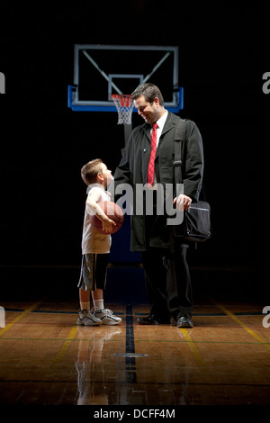 Giovane ragazzo in piedi sul campo da pallacanestro con suo padre Foto Stock