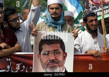 I sostenitori e gli attivisti di Jamat-e-Islami (JI) stanno dimostrando per esprimere la loro solidarietà con il popolo d'Egitto e i sostenitori di morsi, a M.A Jinnah Road a Karachi il Venerdì, 16 agosto 2013. I dimostranti trasportare carte gioco scritto slogan in favore morsi e anti esercito egiziano, manifestanti masterizzare noi bandiera durante la protesta e condanna fermamente la brutale repressione dell esercito contro le persone innocenti di Egitto, compresi donne e bambini e ha detto che il generale dell esercito Al-Saysee sarà sicuramente pagare per questo brutale atto. Foto Stock