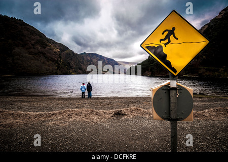 Lago a Glendalough Irlanda con segnale di avviso e due bambini piccoli Foto Stock