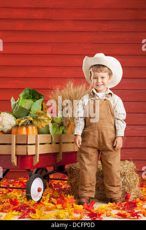 Un ragazzo vestito come un contadino con un carro pieno di produrre; tre colline, Alberta, Canada Foto Stock