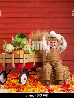 Un ragazzo vestito come un contadino con un carro pieno di produrre; tre colline, Alberta, Canada Foto Stock