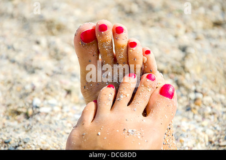 Donna di piedi con red toenails nella sabbia Foto Stock