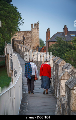 Due 2 persone camminando sulle mura della città di York bar muro romano pareti verso Micklegate antico cerimoniale di entrata nello Yorkshire, Inghilterra. Foto Stock