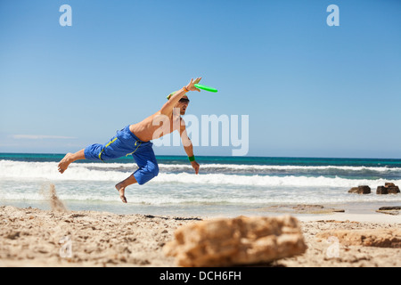 Attraente uomo giocando frisby sulla spiaggia in estate sport fitness jump Foto Stock