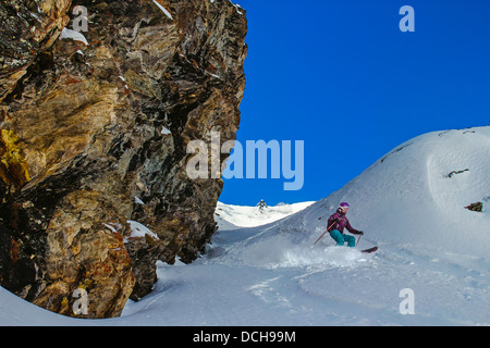 Due gli sciatori in una stretta gola sotto la roccia a strapiombo in montagna Foto Stock