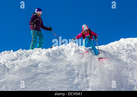 Bambina e una donna adulta sciare nelle montagne contro il cielo blu. Nelle giornate di sole, Foto Stock