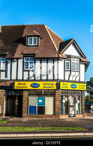 Tende/tendaggi/tende tapparelle/shop, con appartamenti sopra, sul villaggio di Banstead High Street, su di una tranquilla domenica mattina nel Surrey, Inghilterra, Regno Unito. Foto Stock