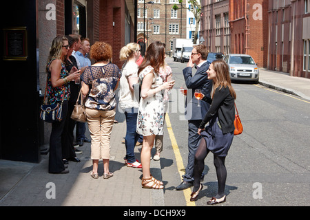Gli uomini e le donne in piedi al di fuori di un wine bar nella città di Londra di bere e fumare England Regno Unito Foto Stock