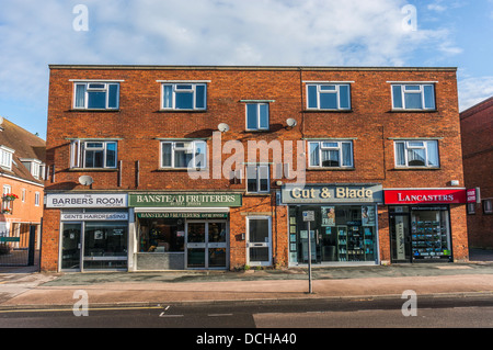 Blocco indipendente di negozi locali con appartamenti sopra, sul villaggio di Banstead High Street, su di una tranquilla domenica mattina nel Surrey, Inghilterra, Regno Unito Foto Stock