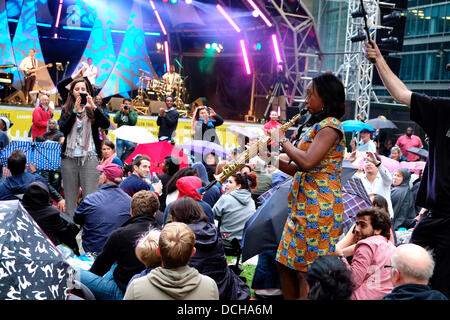 Yolanda Brown il sassofonista jazz incanta la folla come la pioggia inizia a cadere al Canada Square Park, Londra, UK, 17 agosto 2013. Foto Stock