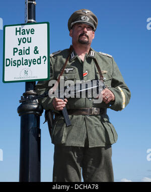 Lytham, Blackpool. 18th agosto, 2013. Simon carter di Tarleton un re-enactor che indossa il costume di un soldato tedesco, vicino a parcheggio a pagamento e mostra, al Lytham 3rd annuale 1940's Wartime Festival, 1940s era, quaranta fine settimana di guerra, reenactment wartime tenuto su Lytham Green, Lancashire, Regno Unito. Foto Stock