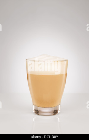 Piccolo cappuccino in un bicchiere di vetro su uno sfondo grigio Foto Stock