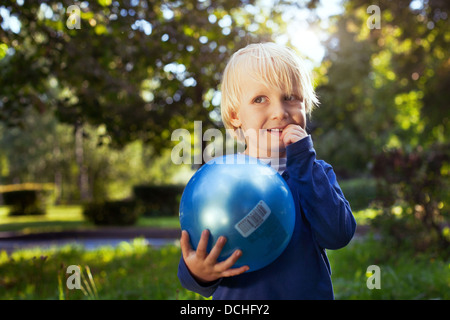 Poco carino ragazzo con la palla cercando Foto Stock