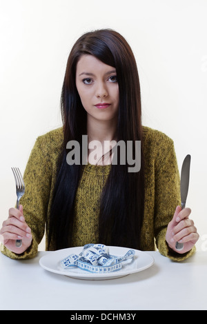 Bella giovane donna mantenendo una dieta e in forma, concetto rappresentato dalla mostra una misura di nastro sulla sua piastra cena Foto Stock