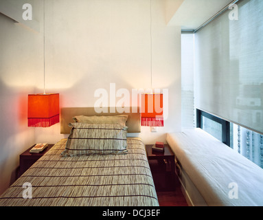 Camera da letto con orange appendere le luci al posto letto in un moderno appartamento cinese, midlevels, Hong Kong. Il design degli interni di Johnny Li. Foto Stock