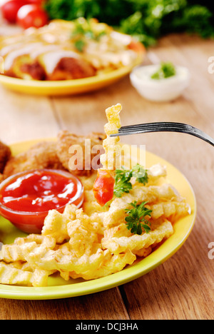 Carni saporite patate fritte e pollo sulla piastra della tavola di legno lungo con verdure Foto Stock