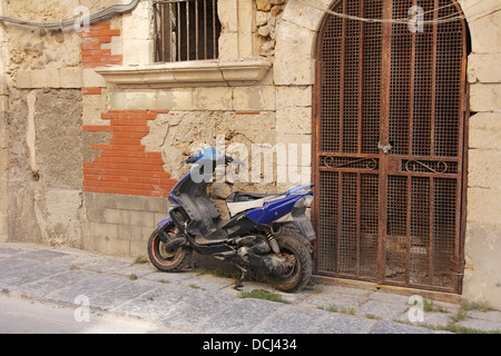 Vecchio arrugginito scooter blu oldtimer moto a sinistra in una strada abbandonata Foto Stock