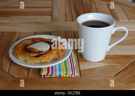 Originale pasticceria danese di laminato di lievito di pasta lievitata - friabile e delicato crosta e una tazza di caffè su una tabella di caffè. Foto Stock