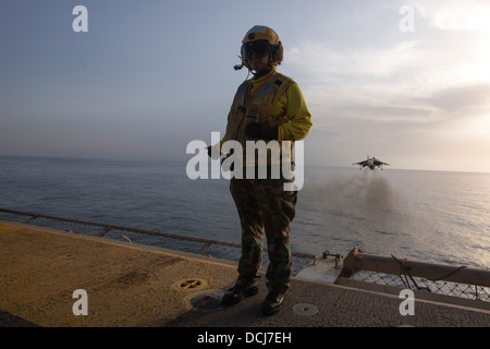 Aviazione di Boatswain Mate (manipolazione) Airman Lucia Pizarro segnali come un AV-8B Harrier decolla dall'assalto anfibio della nave Foto Stock