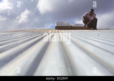 Pannello solare tecnico di effettuare lavori di manutenzione su una lamiera grecata, Regione Miono, Tanzania. Foto Stock