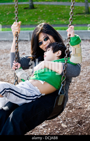 Madre oscillante con suo figlio disabili Foto Stock