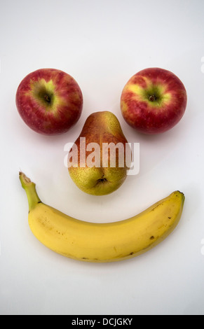 Due mele, una pera e una banana guardando come una faccina sorridente. Foto Stock