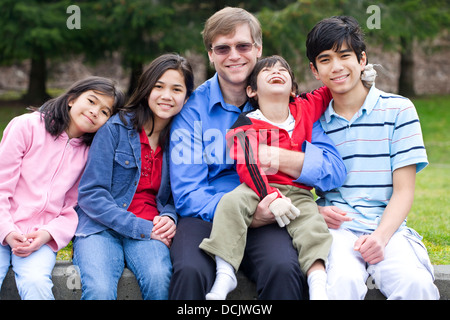 Felice famiglia interraziale godendo di giornata al parco con figlio disabili Foto Stock