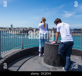 Coppia giovane a guardare le barche immettere Portsmouth Porto dalle fortificazioni a Old Portsmouth Foto Stock