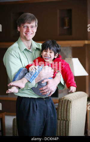 Padre tenendo la sua tre disabili anno vecchio figlio Foto Stock