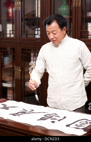 Senior man praticando la calligrafia in studio Foto Stock